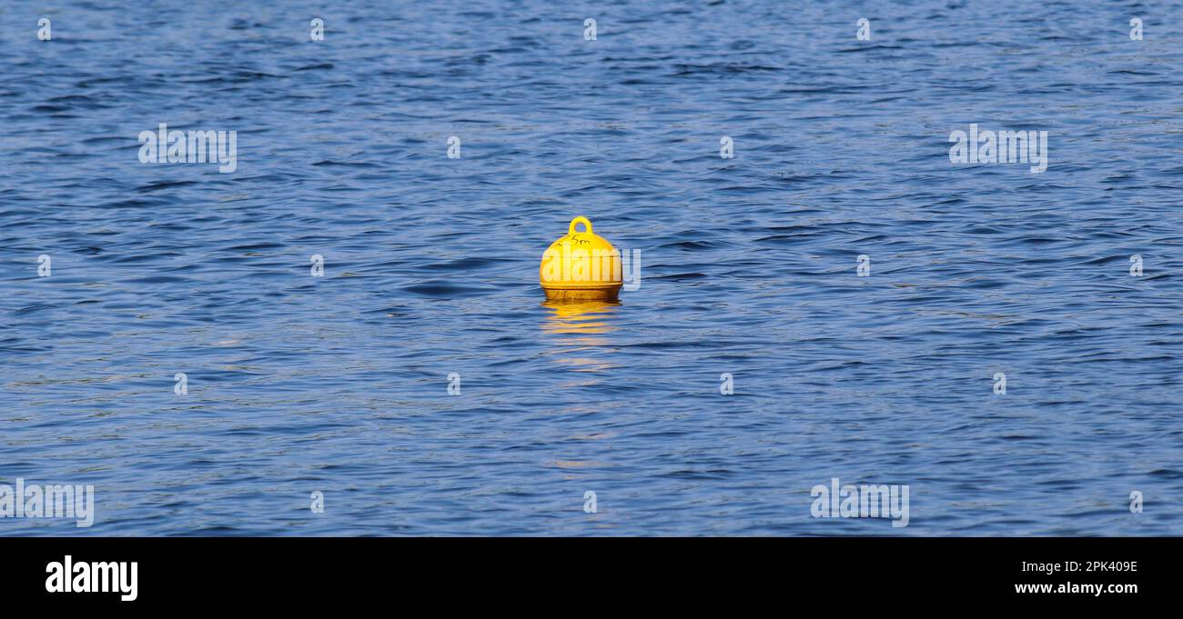 Yellow floating buoy ball on water surface marks boundary of safe