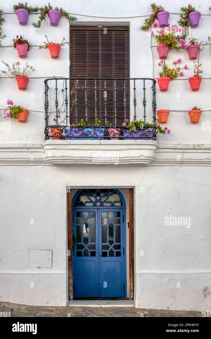 Traditional Andalusian village facade decorated with pots, with blue wooden door and balcony with shutter, in Vejer de la Frontera, a touristic Andalu Stock Photo