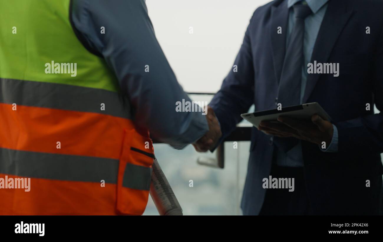 Construction workers shaking hands businesspeople at construction site Stock Photo