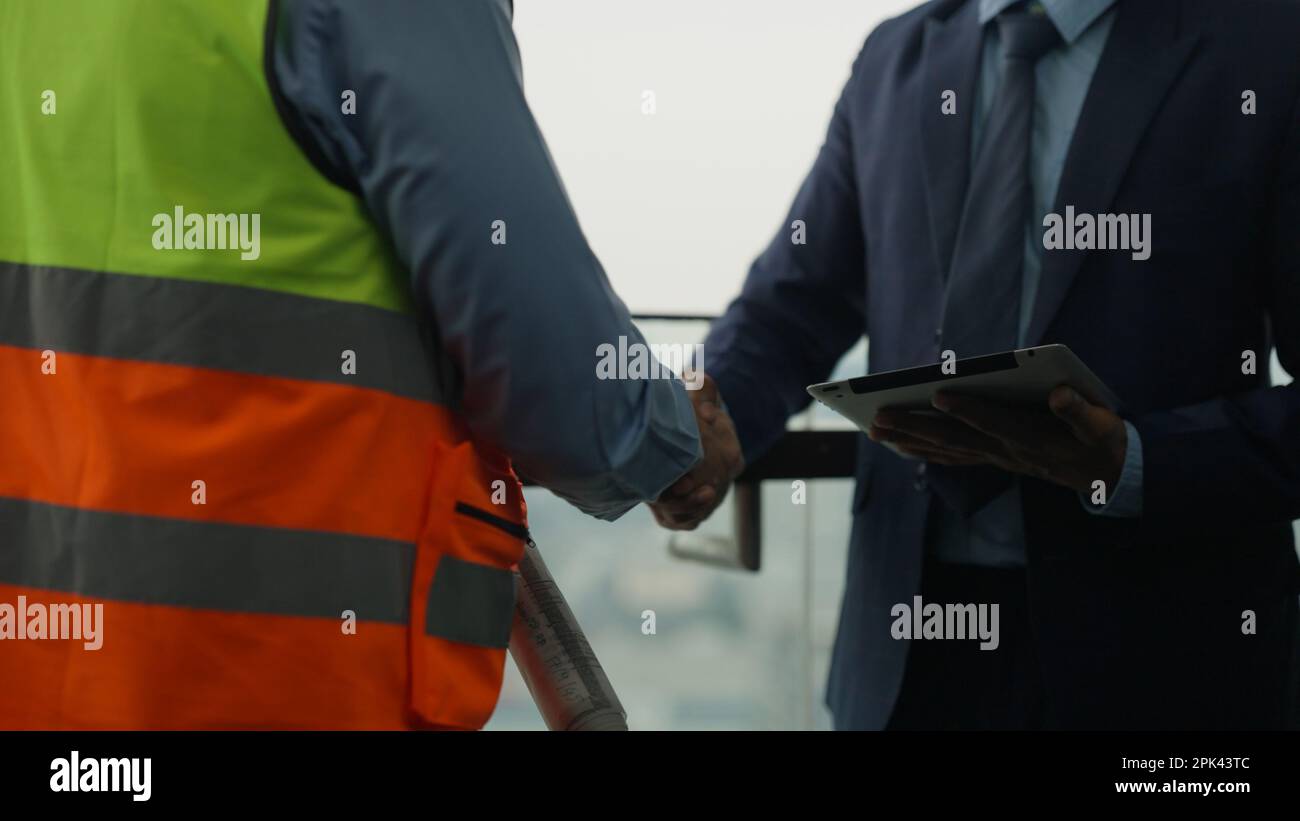 Construction workers shaking hands businesspeople at construction site Stock Photo