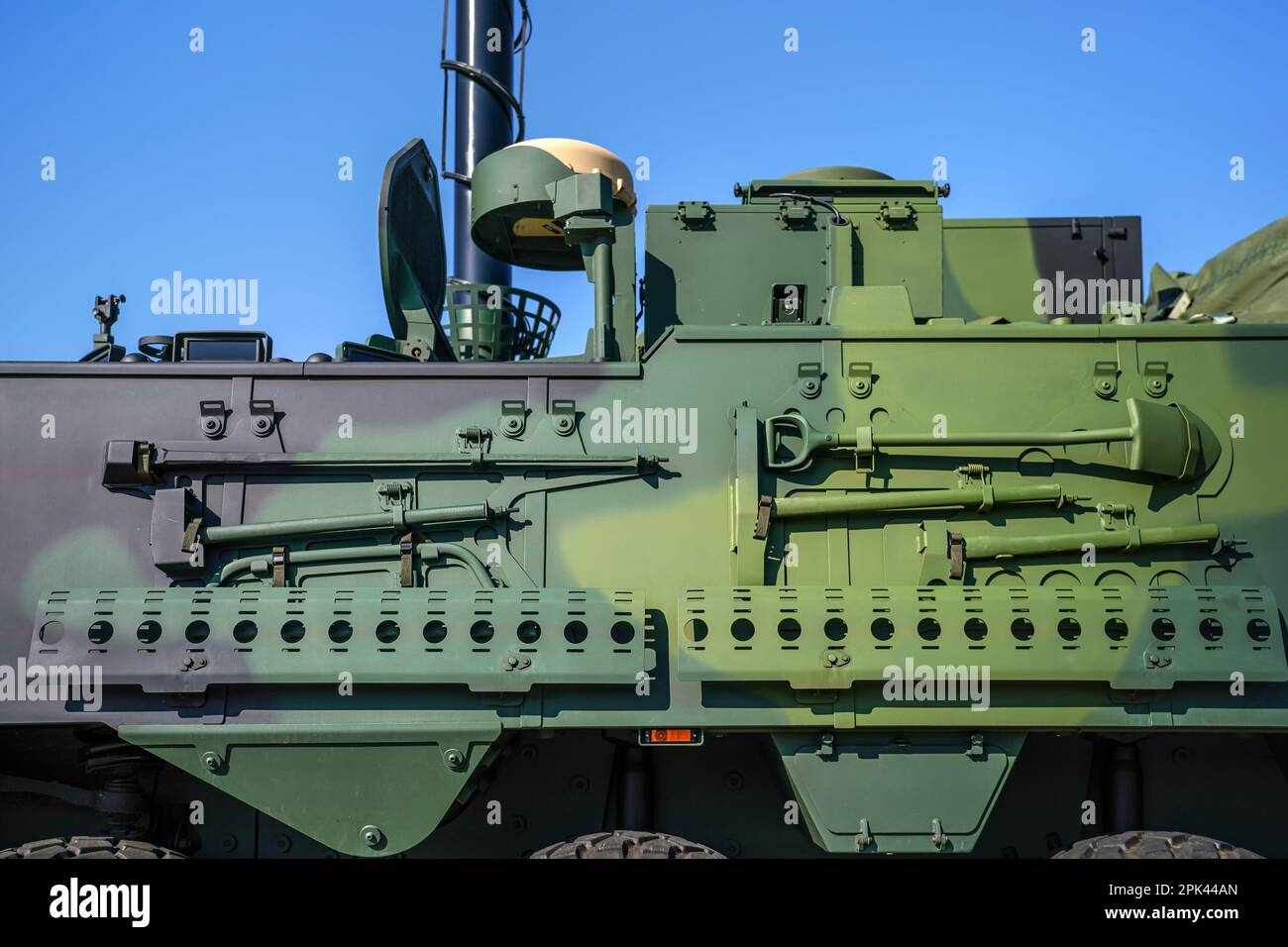 Armoured vehicle side green steel plating, close-up detail to pole, shovel and other tools mounted on wall Stock Photo