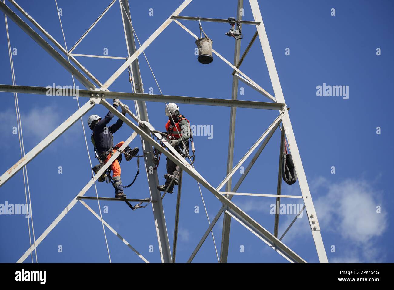 Electricians work overhead to dismantle a high voltage pylon for replacement. Milan, Italy - April 2023 Stock Photo