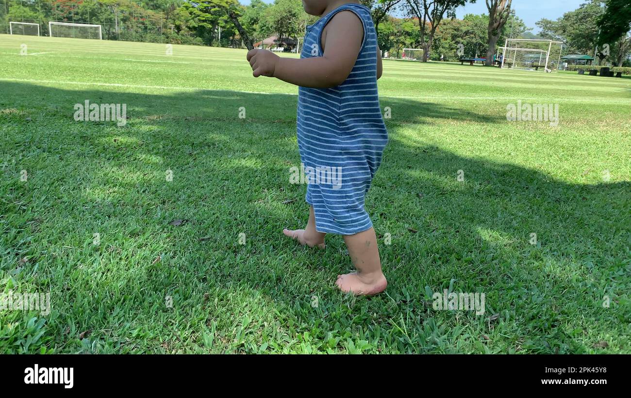 Baby infant walking barefoot on grass outside Stock Photo Alamy