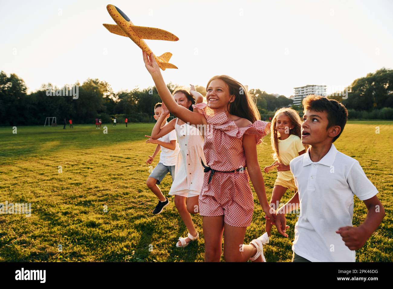 Playing with toy plane. Group of happy kids is outdoors on the sportive ...