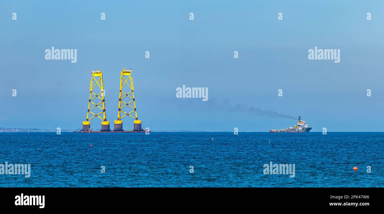 Ship towing barge with yellow wind turbine platforms out to North Sea, Firth of Forth, Scotland, UK Stock Photo