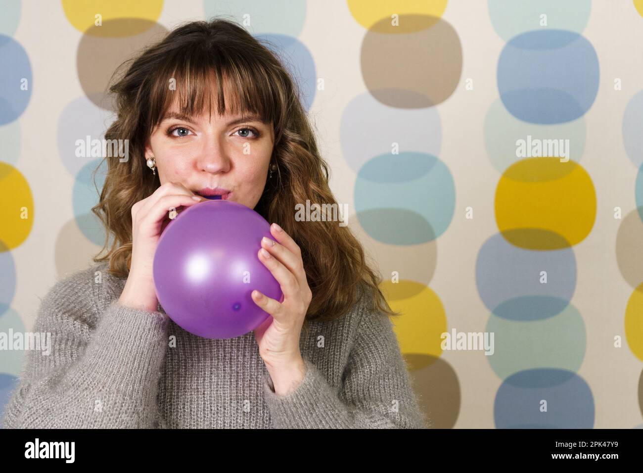 Young Woman Blowing a Purple Balloon Stock Photo