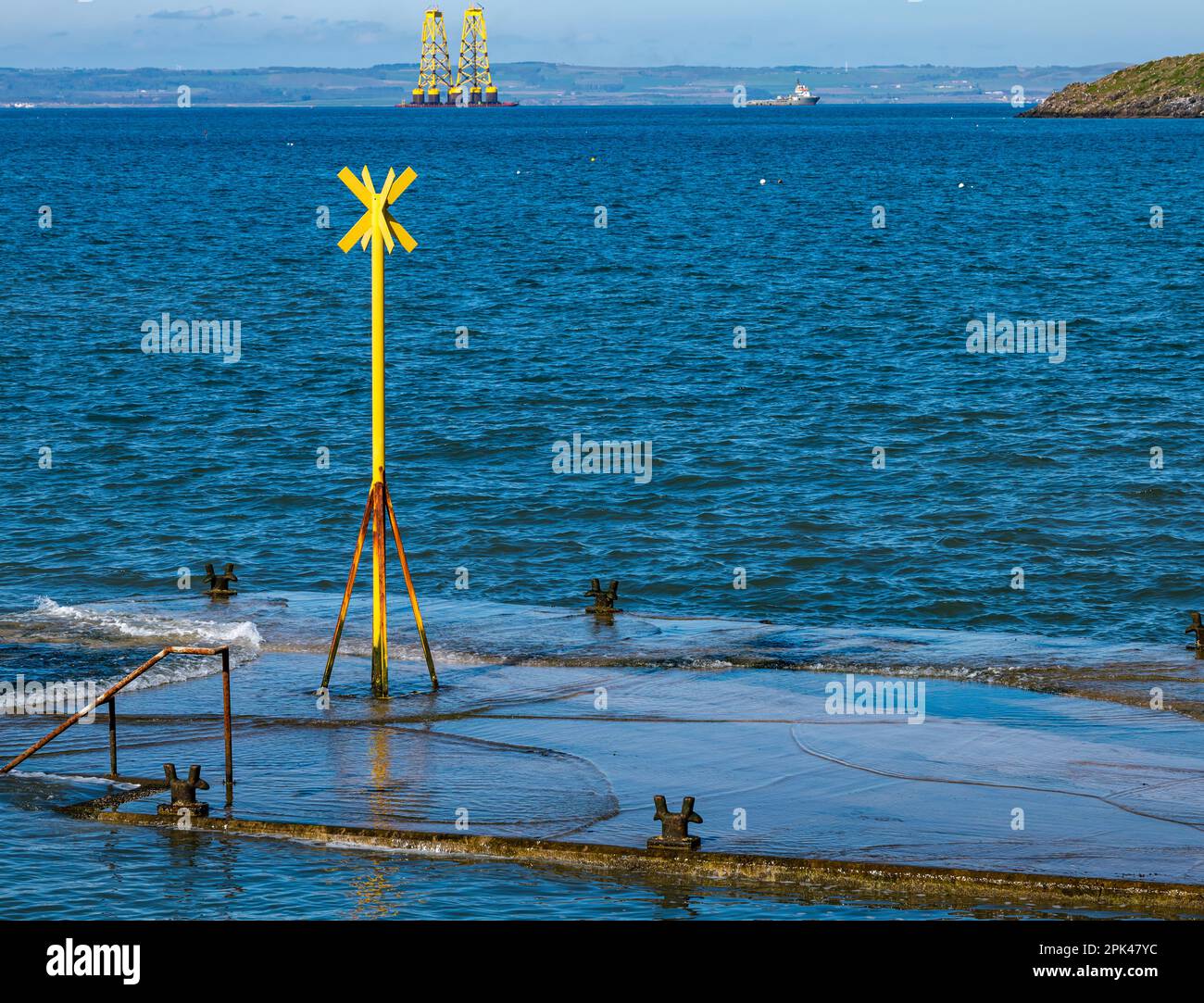 Ship towing barge with yellow wind turbine platforms out to North Sea, North Berwick, Firth of Forth, Scotland, UK Stock Photo