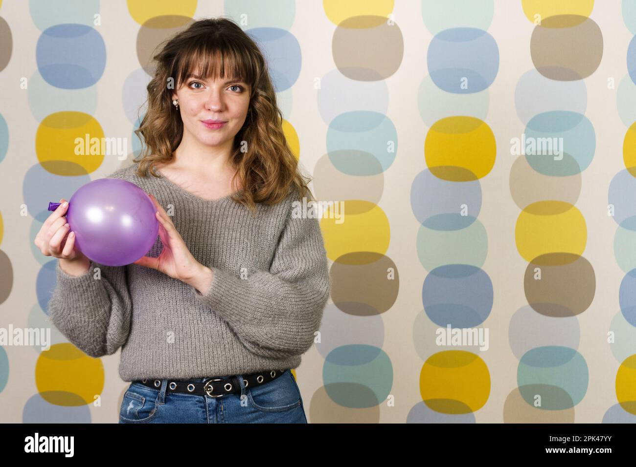 Young Woman Holding and Deflating a Purple Balloon Stock Photo