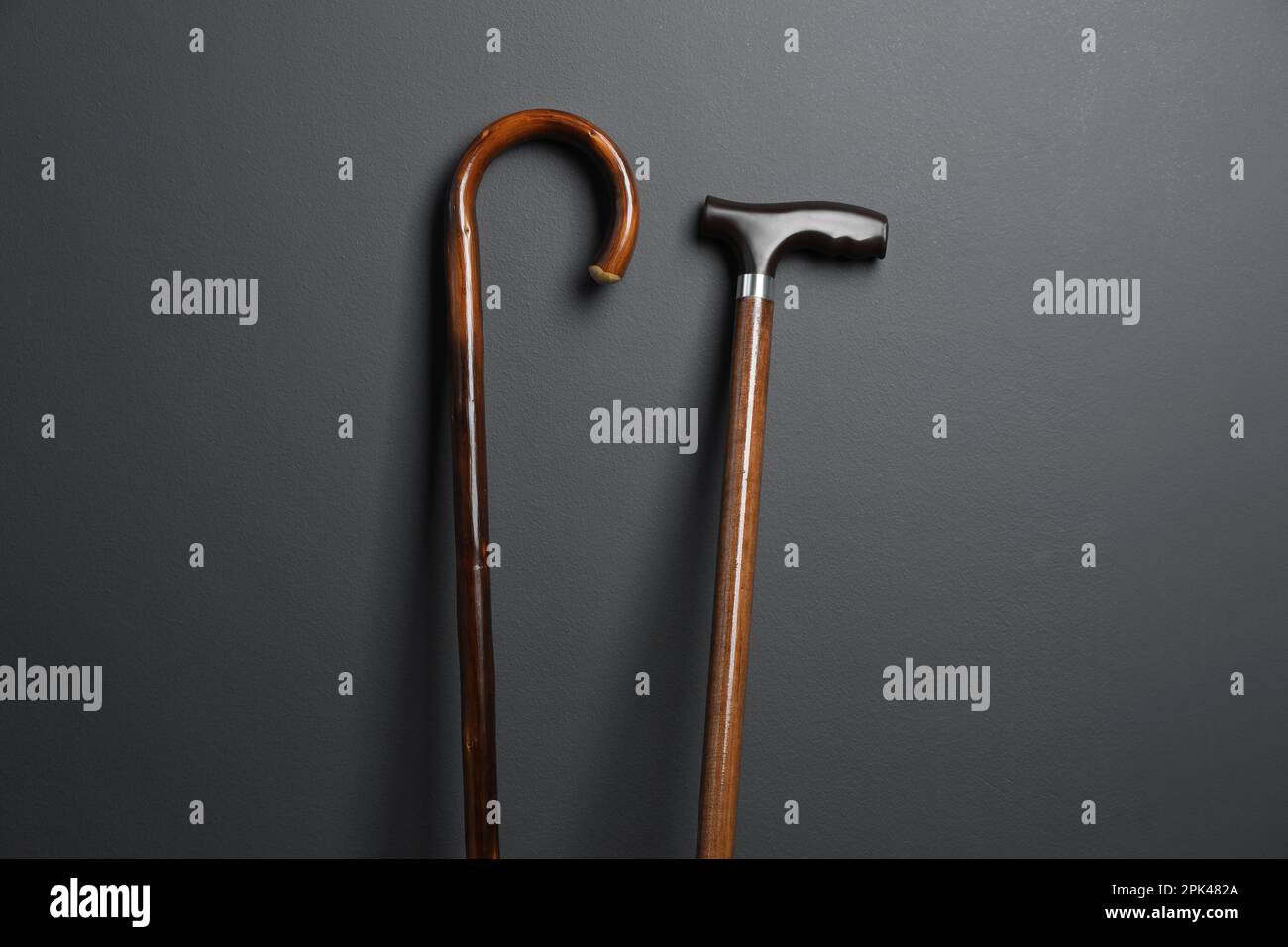 Different wooden walking canes on grey background Stock Photo