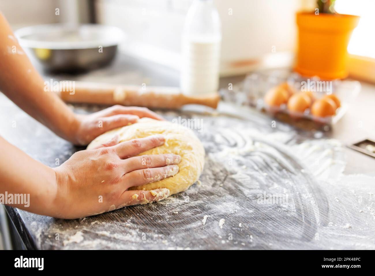 Womens hands kneading dough on table sprinkle with flour. Kneading dough Stock Photo