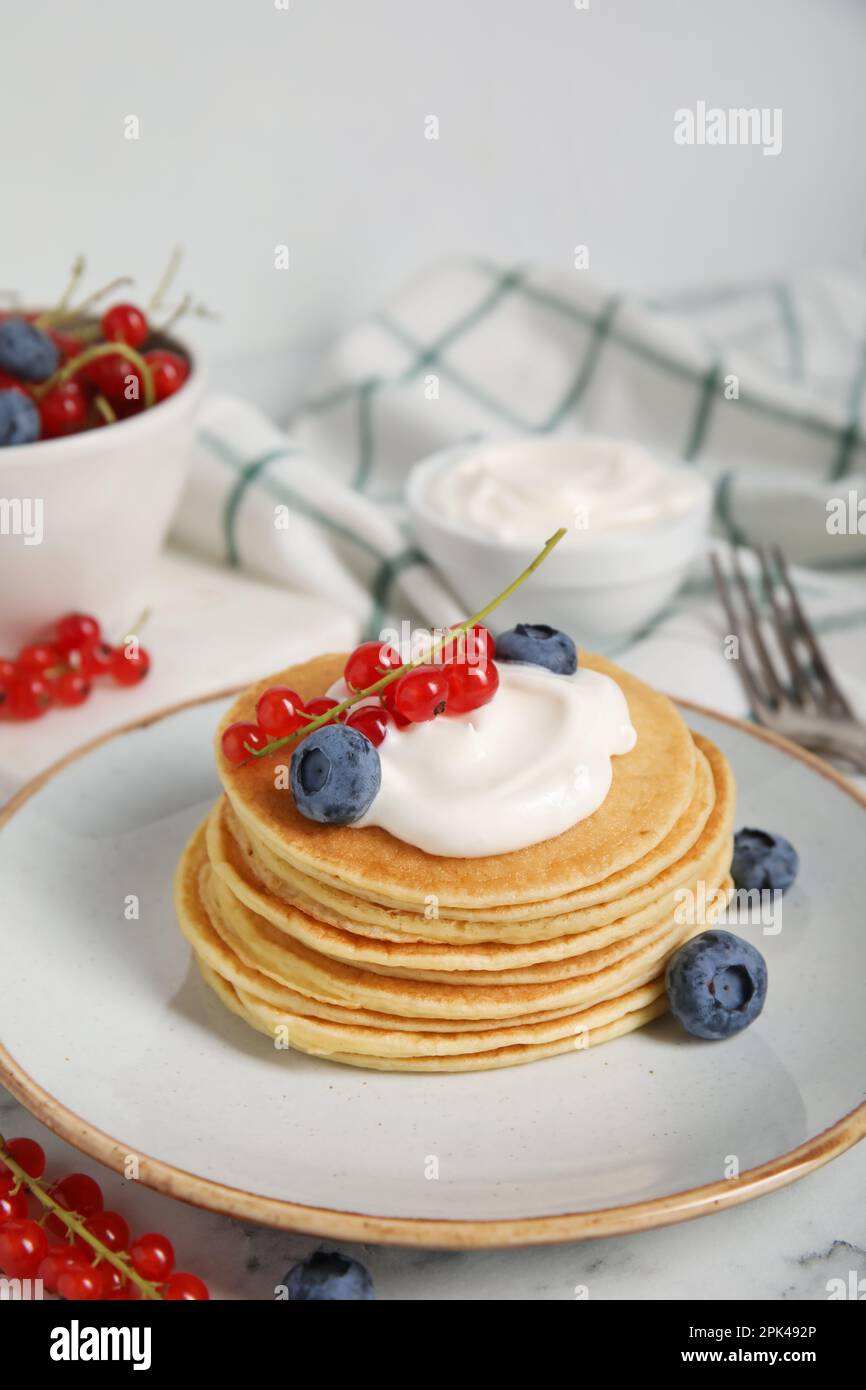 Tasty pancakes with natural yogurt, blueberries and red currants on marble table Stock Photo