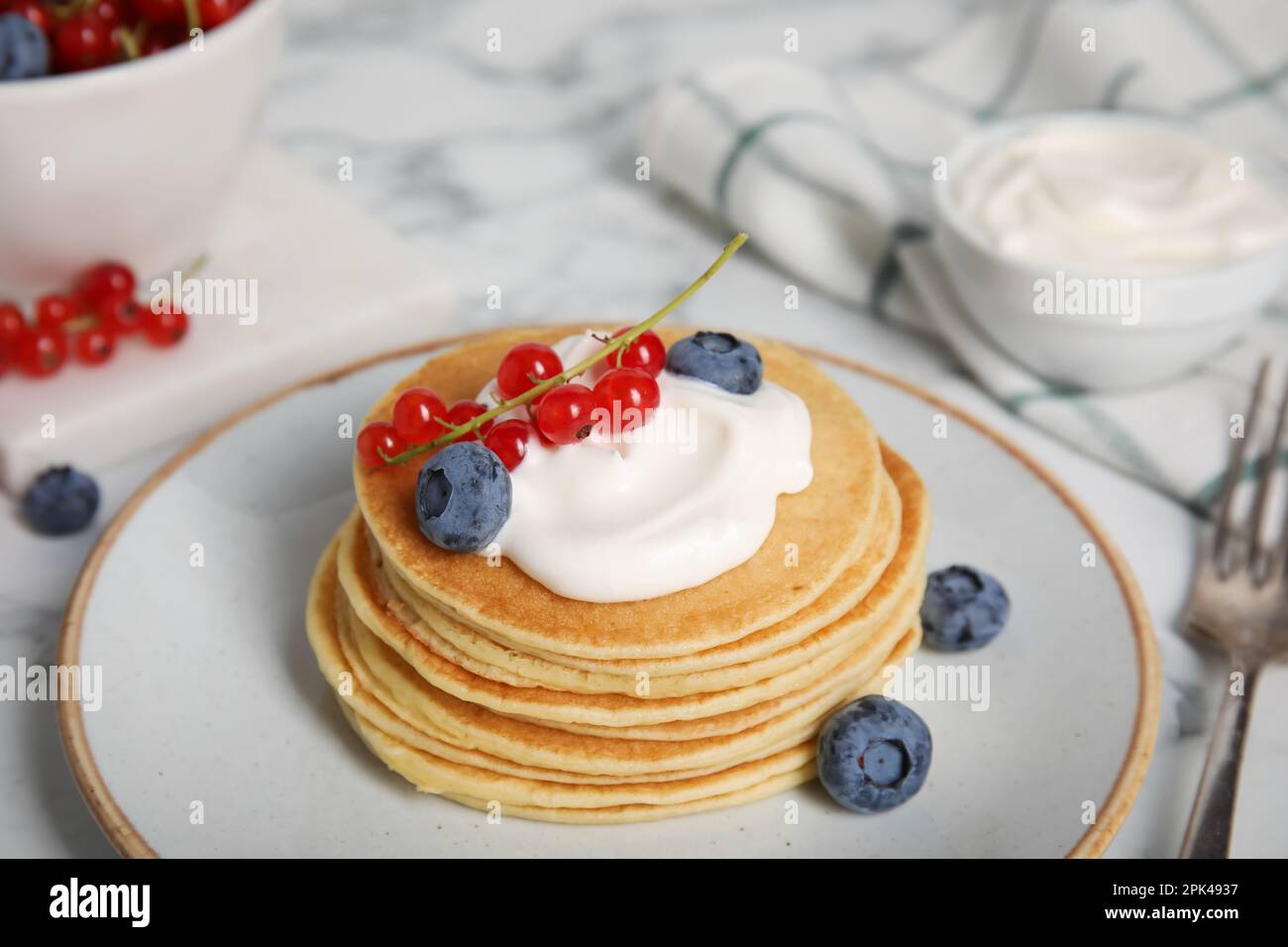 Tasty pancakes with natural yogurt, blueberries and red currants on marble table Stock Photo