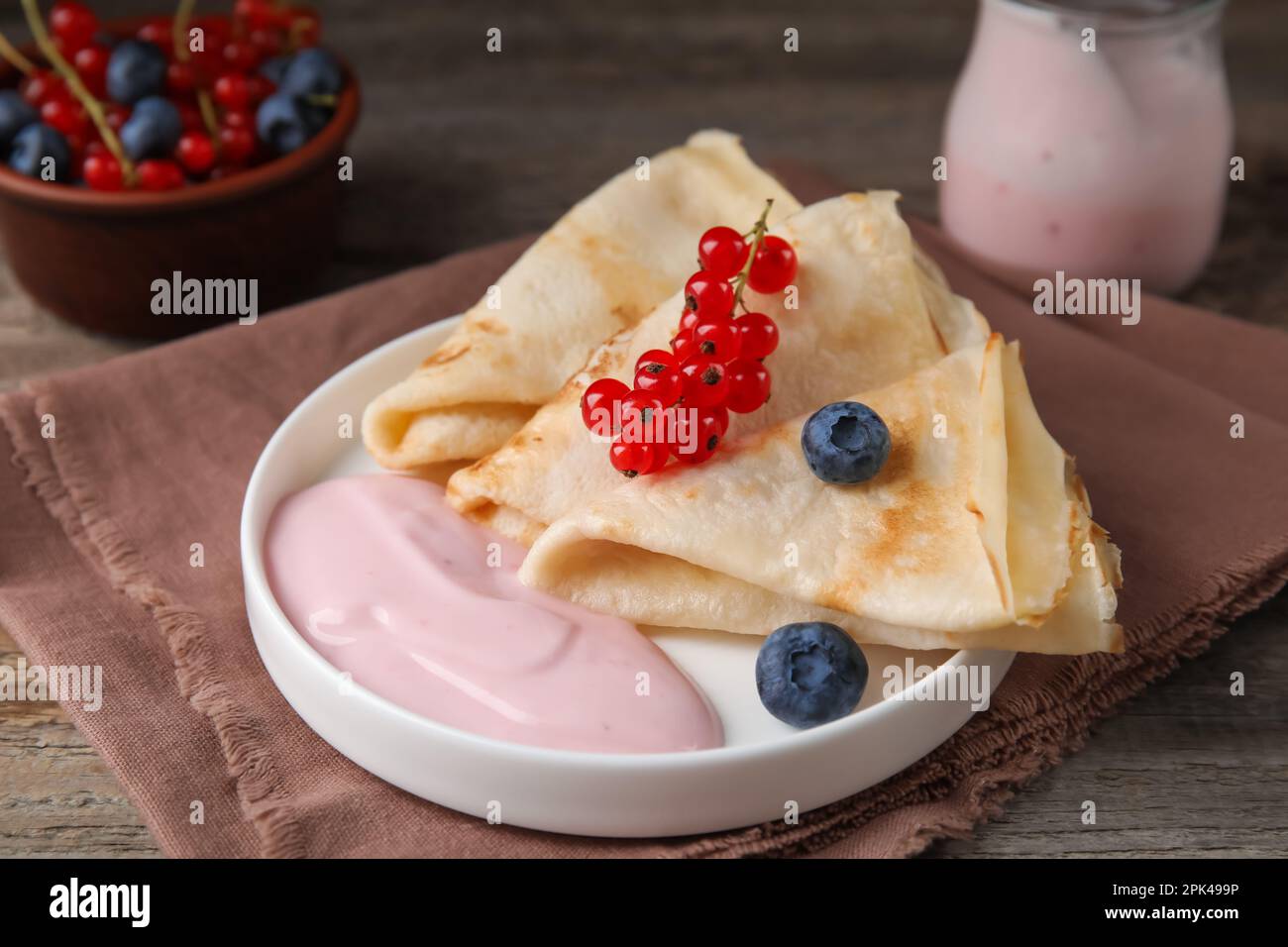Delicious crepes with natural yogurt, blueberries and red currants on wooden table Stock Photo