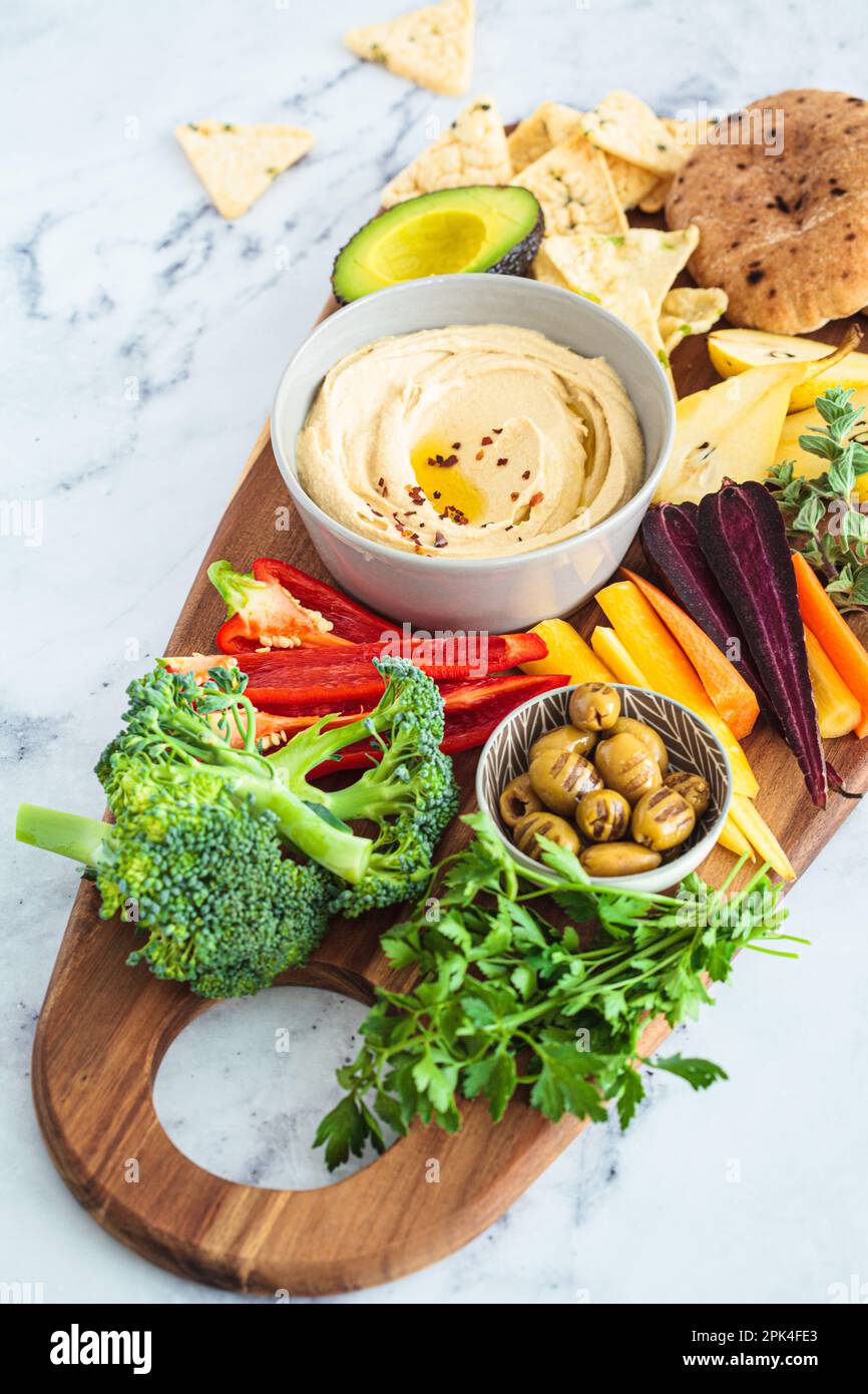 Vegetarian snack board with hummus, vegetables, fruits, olives, pita