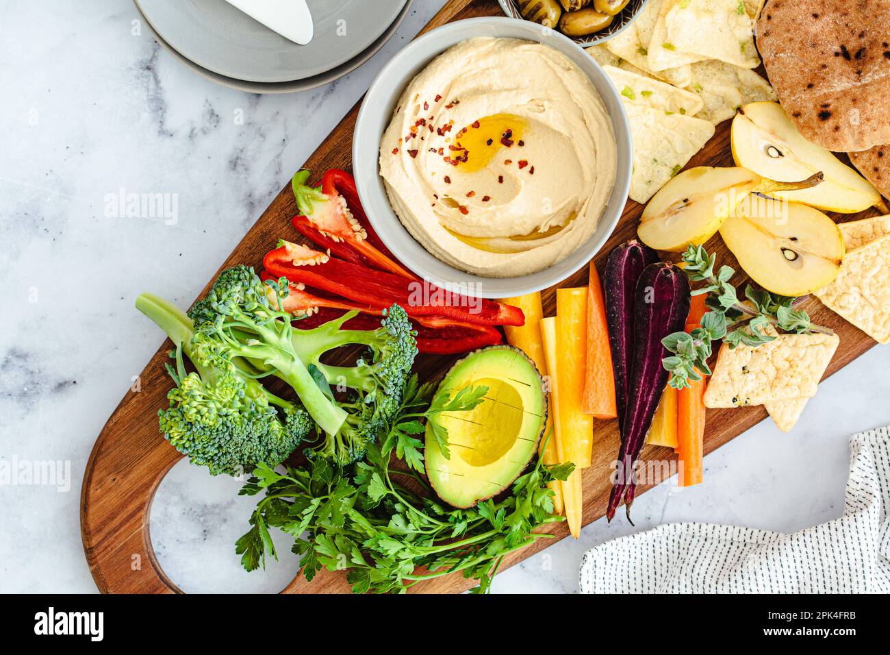 Vegetarian snack board with hummus, vegetables, fruits, olives, pita