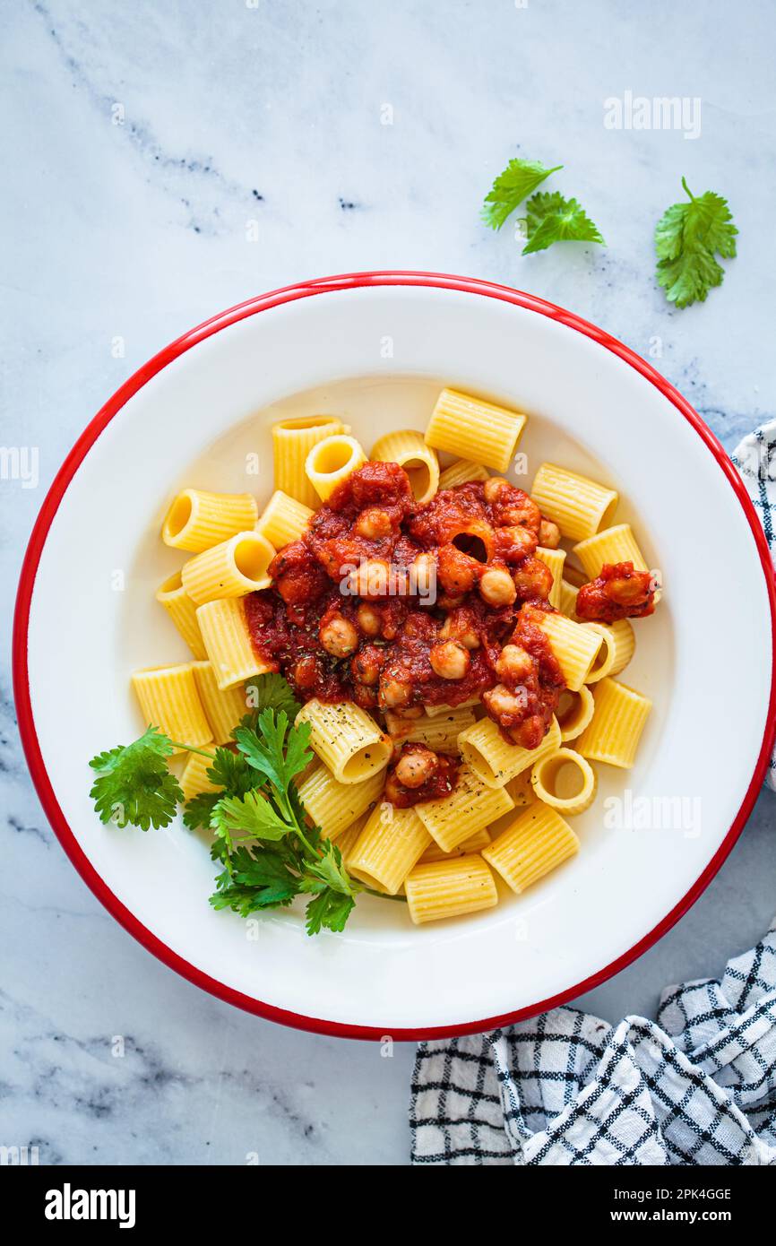 Vegan rigatoni pasta with chickpeas and tomato sauce in white plate
