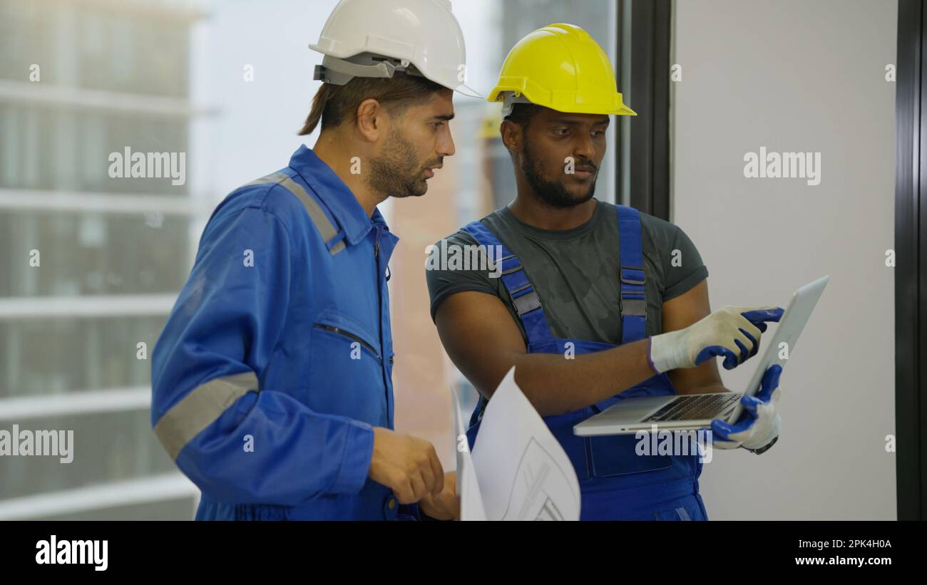 Contractor worker and professional architect holding laptop talking Stock Photo