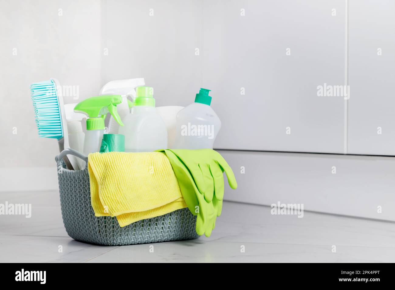 Cleaning ecological chemical products for cleaning, detergent bottles, disinfection at home in a basket on tile floor in light interior Stock Photo