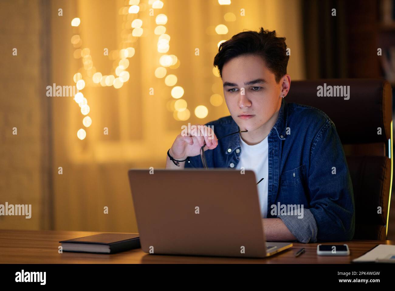 Pensive young caucasian guy developer working on laptop Stock Photo