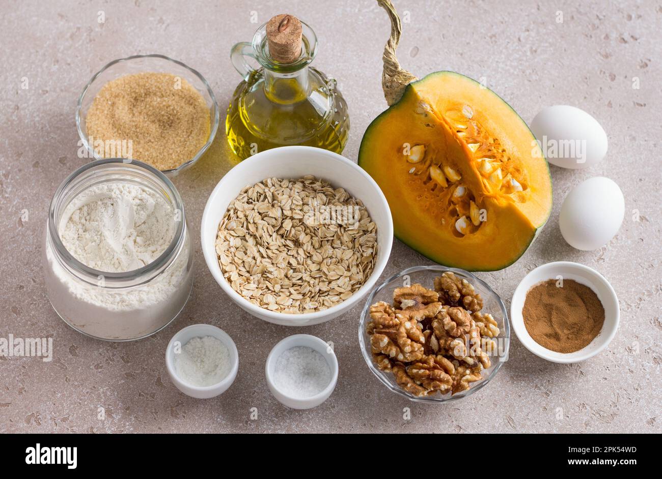 Ingredients for pumpkin muffins or casseroles: pumpkin, wheat flour, oatmeal, brown sugar, olive oil, walnuts, eggs and spices, home cooking on a beig Stock Photo