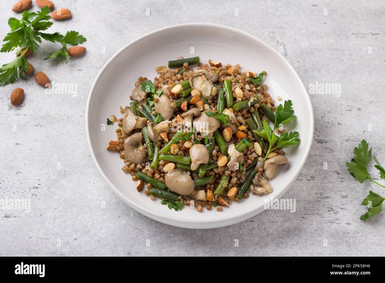 A simple steamed vegan dish. Buckwheat with green beans, oyster mushrooms, almonds and parsley, top view. Delicious healthy homemade food Stock Photo