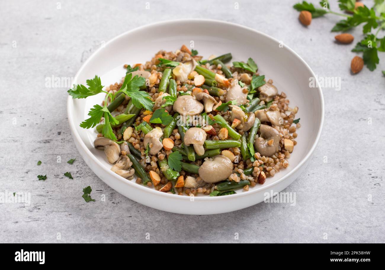 A simple steamed vegan dish. Buckwheat with green beans, oyster mushrooms, almonds and parsley, top view. Delicious healthy homemade food Stock Photo