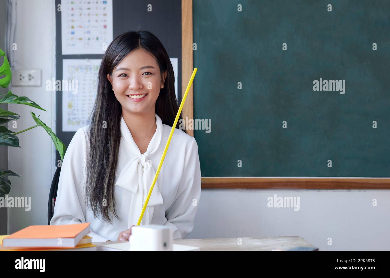 Teacher sitting near backboard posing to camera with smile Stock Photo