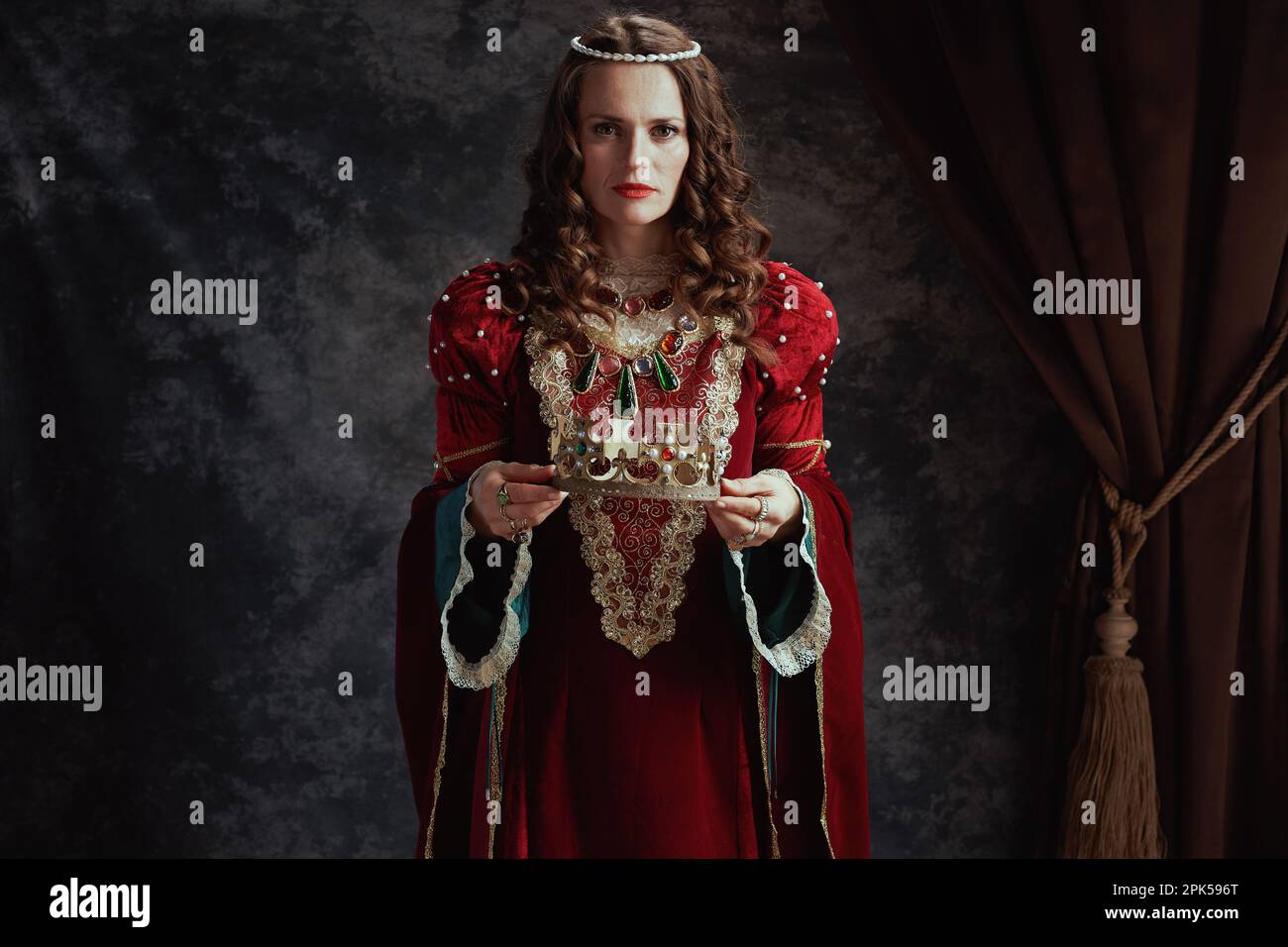 medieval queen in red dress with crown on dark gray background Stock ...