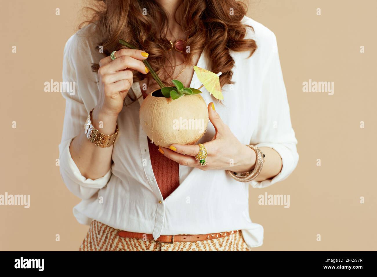 Beach vacation. Closeup on woman against beige background with coconut cocktail. Stock Photo