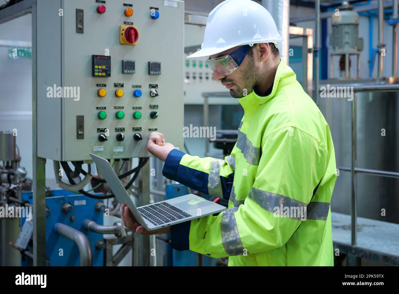Engineer specialist using laptop checking and maintaining machine in factory Stock Photo