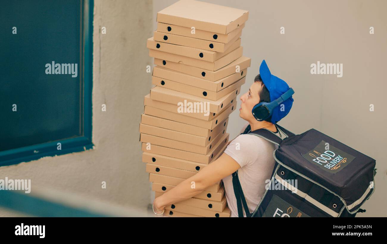 Clumsy food courier trying to catch falling pizza boxes, acting scared