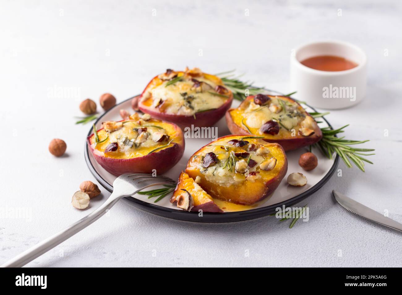 Baked peaches with blue cheese, hazelnuts, rosemary, served with honey