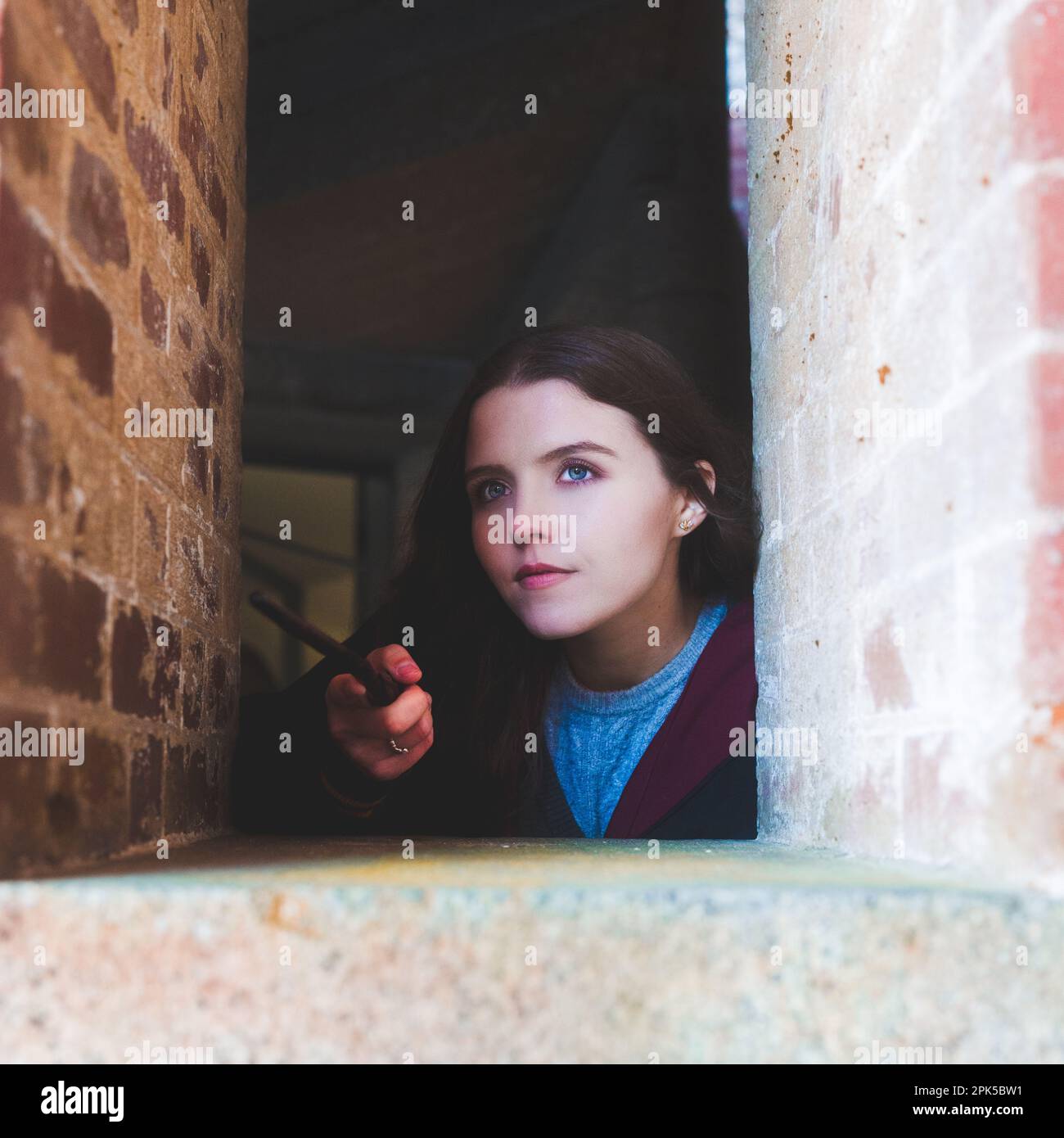 Young Witch Holding a Wand Guarding a Fortress | Harry Potter Robes Stock Photo