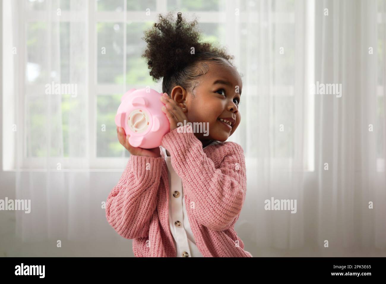 Little girl putting coin of cash into ceramic piggy bank Stock Photo ...