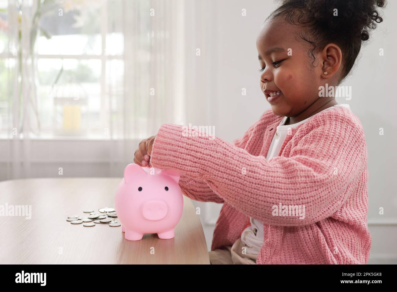 Little girl putting coin of cash into ceramic piggy bank Stock Photo ...