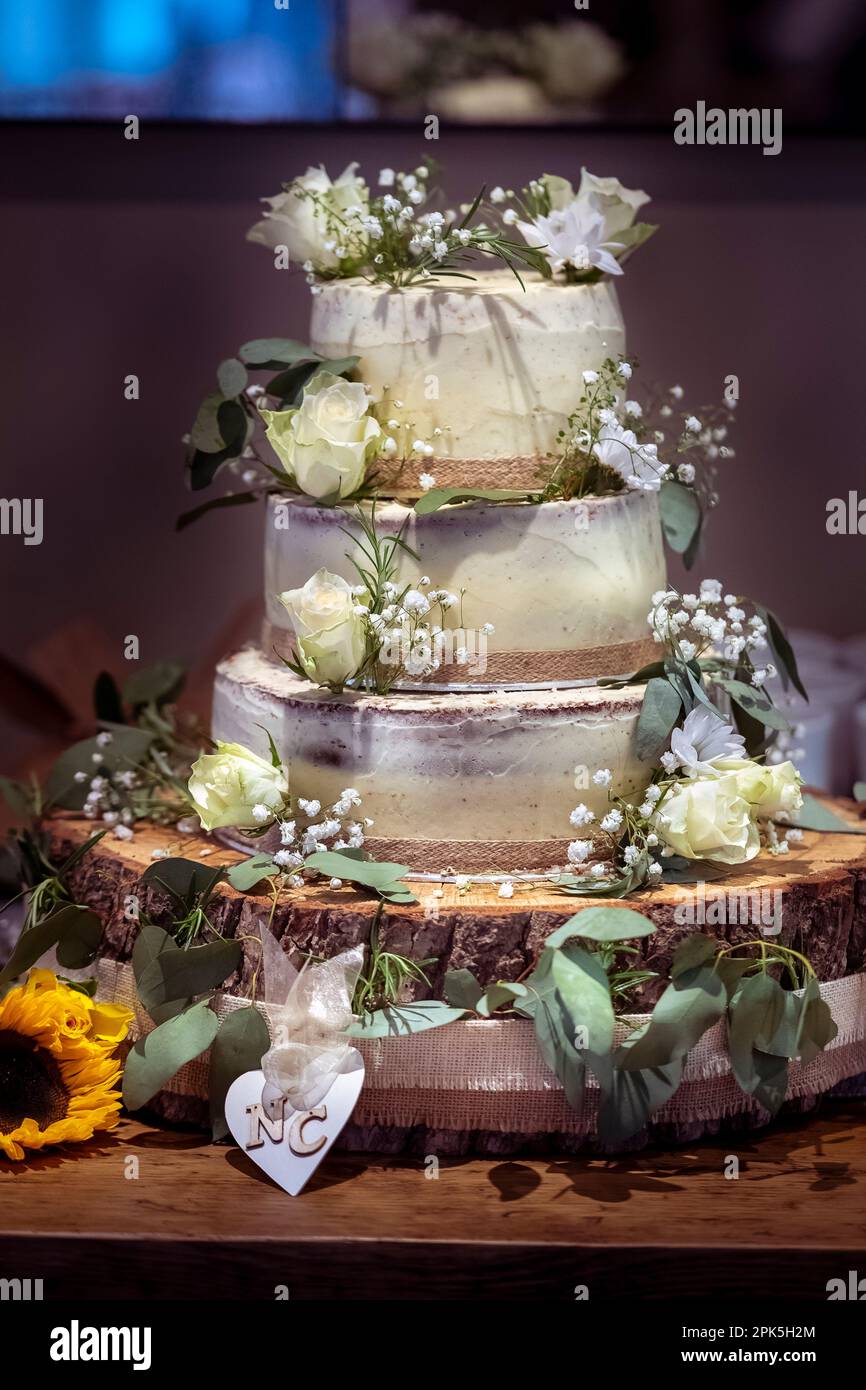 Wedding cake, three tier cake, layers, sitting on wood block. Stock Photo