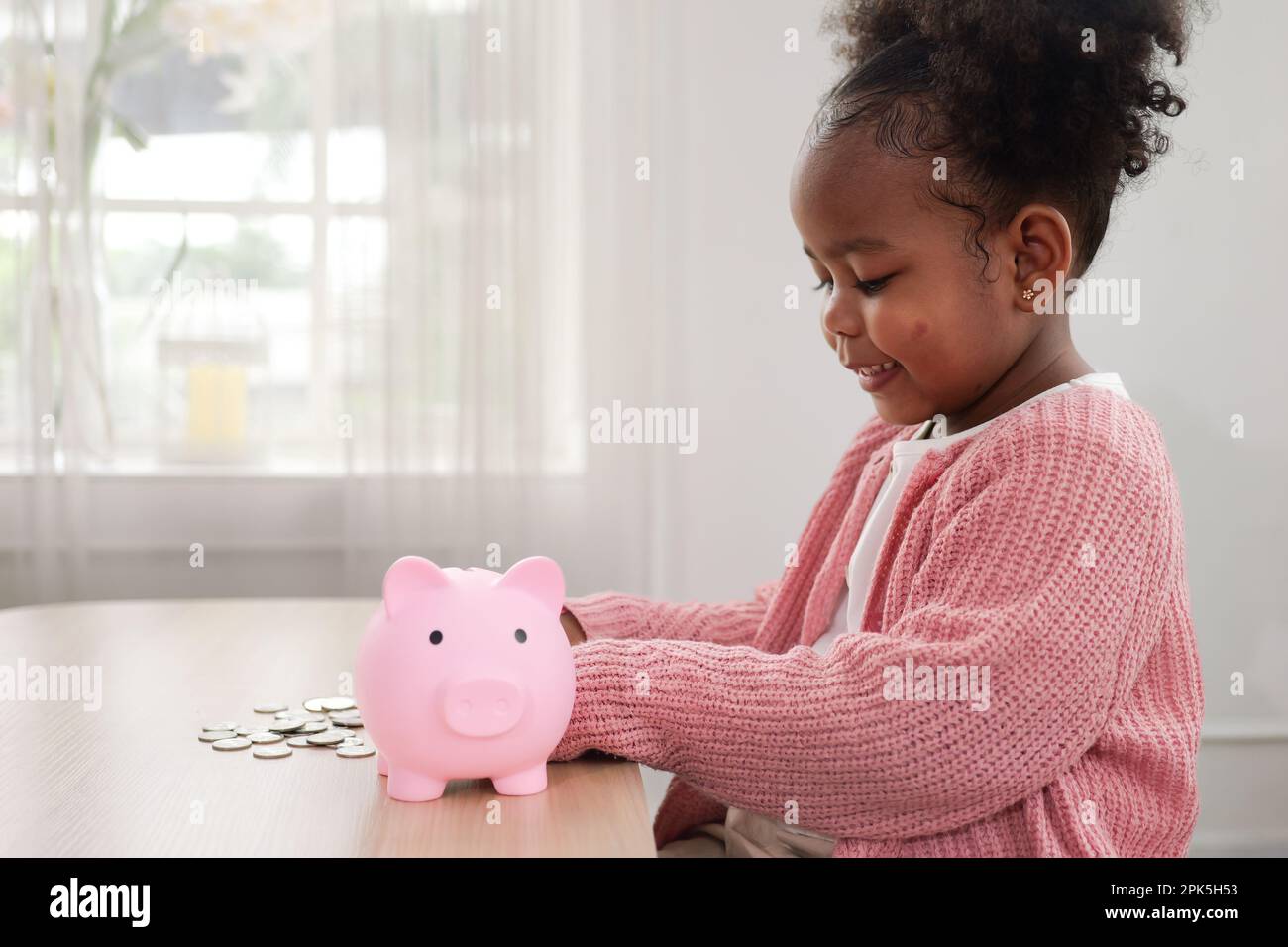 Little girl putting coin of cash into ceramic piggy bank Stock Photo ...