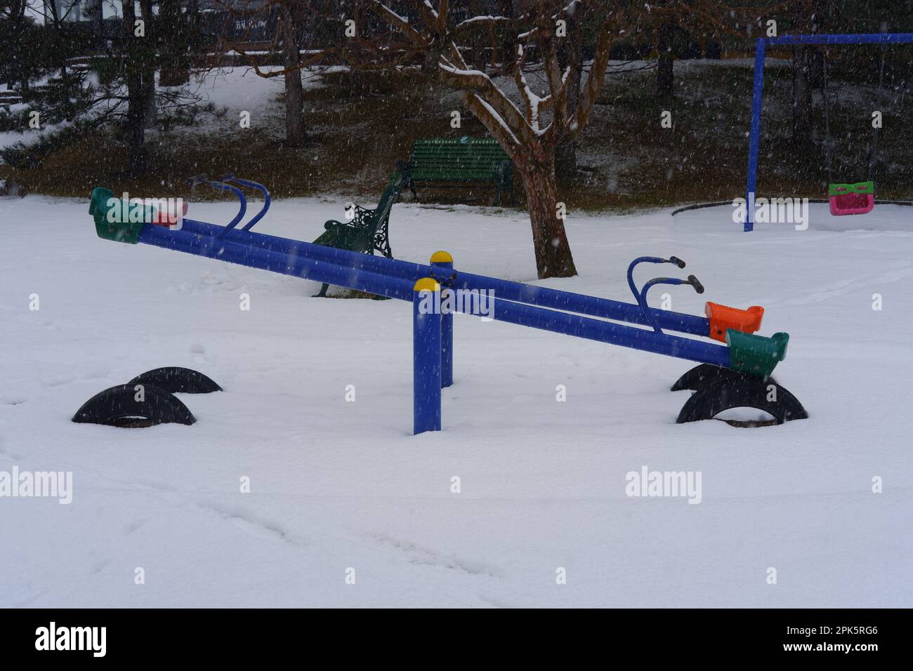 Teeter-totter at Children Playground In Public Park Covered With Winter Snow Stock Photo