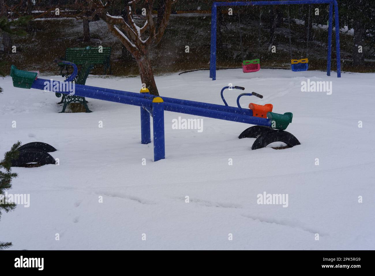Teeter-totter at Children Playground In Public Park Covered With Winter Snow Stock Photo