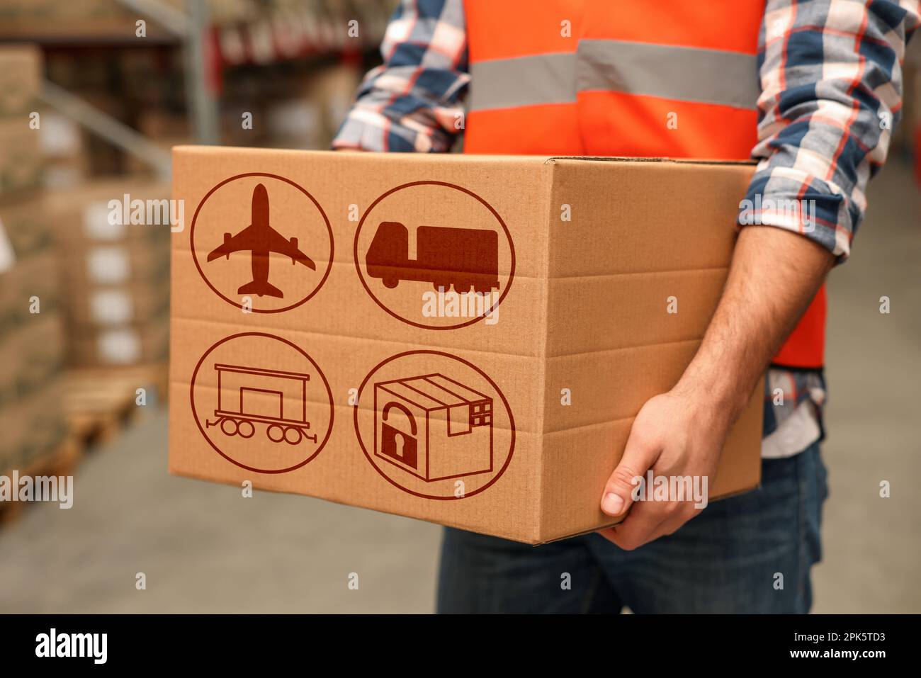 Worker with cardboard box with shipping icons in warehouse, closeup ...