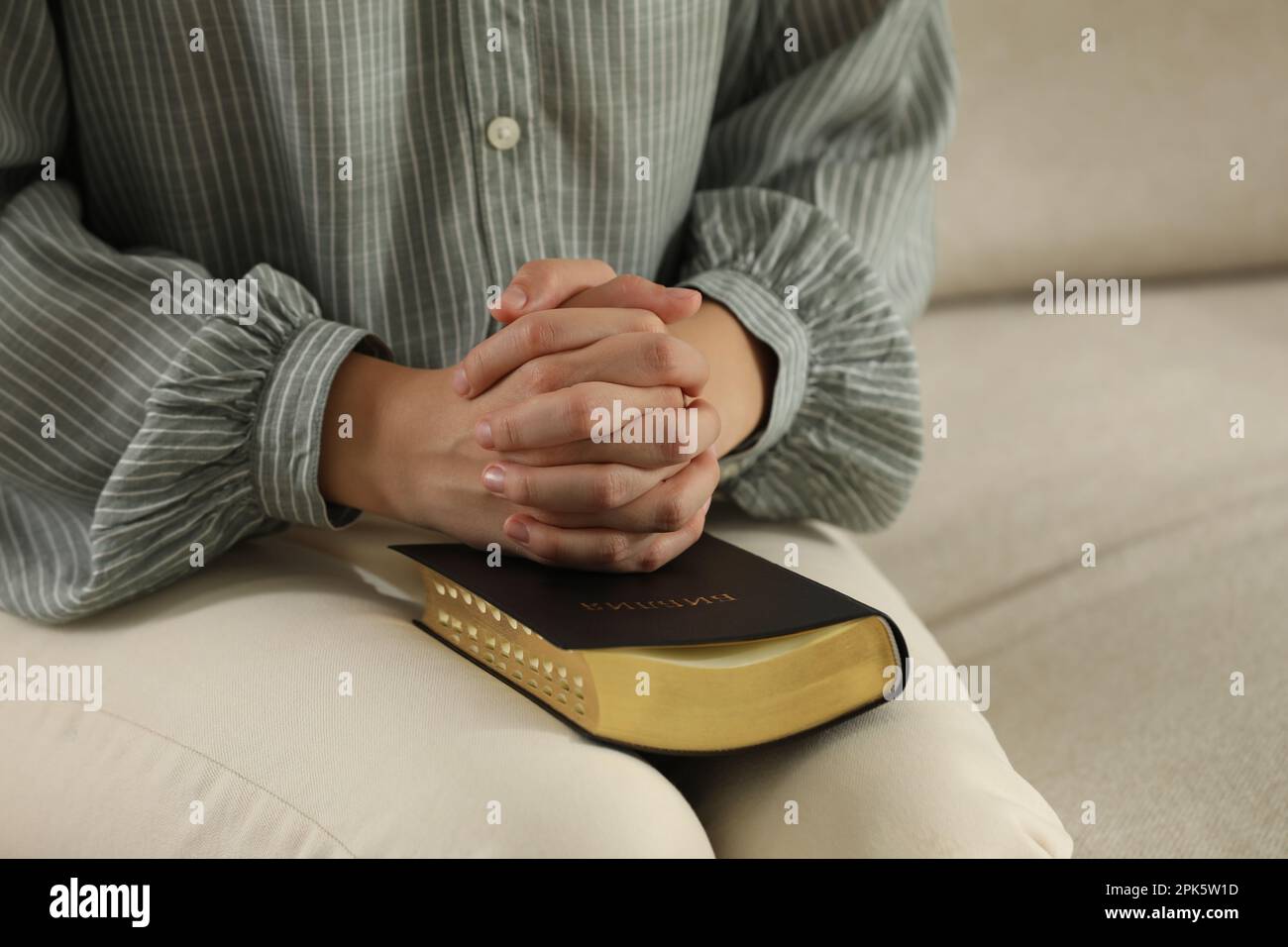 Religious woman praying over Bible on sofa, closeup Stock Photo Alamy
