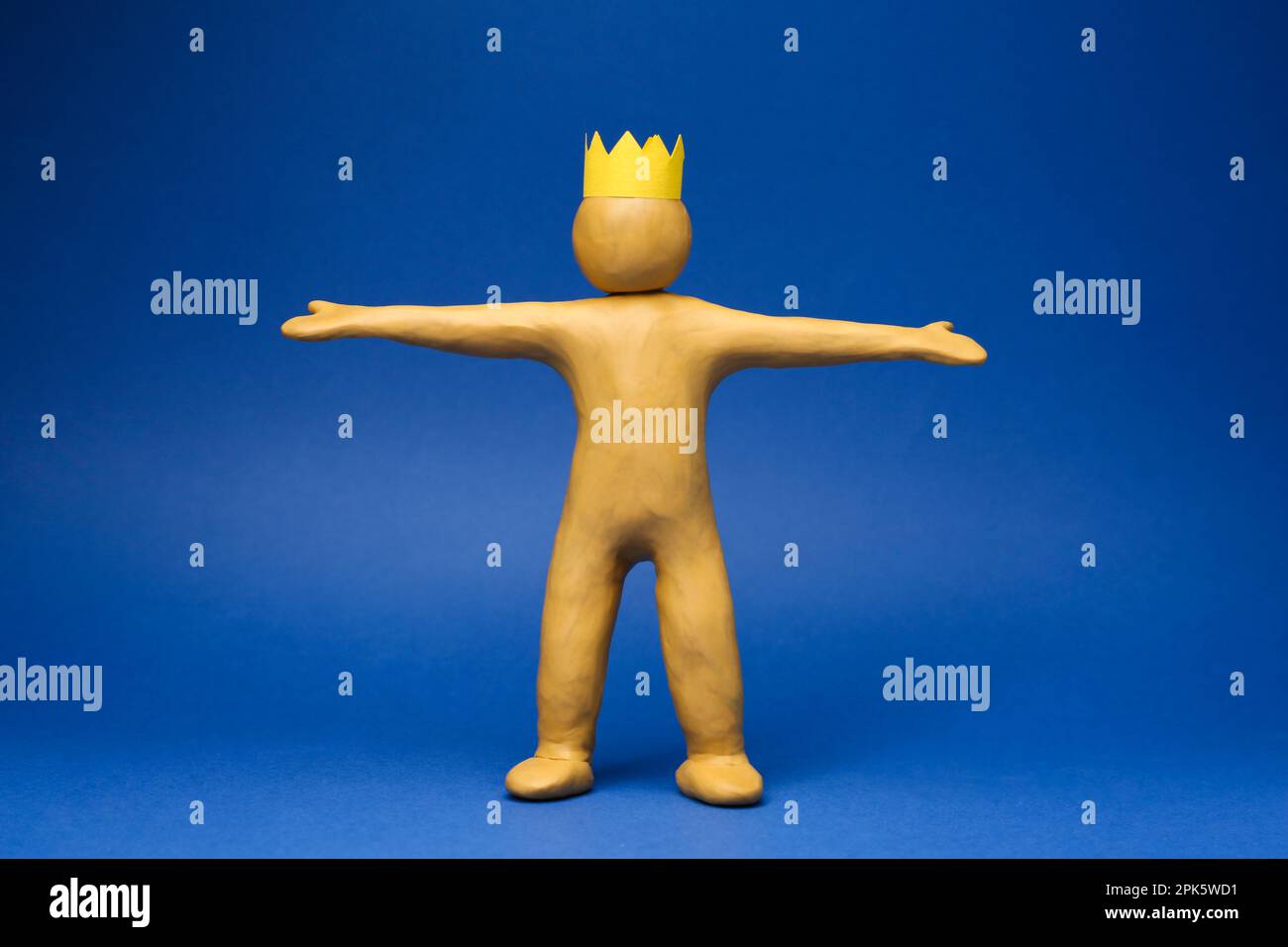 Plasticine figure with crown on head against blue background Stock Photo