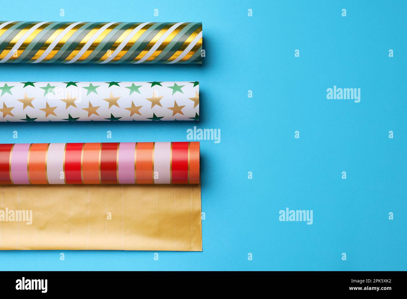 Different colorful wrapping paper rolls on light blue background, flat ...