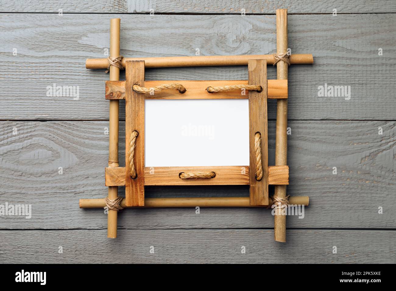 Empty bamboo frame on grey wooden background, top view. Space for text ...