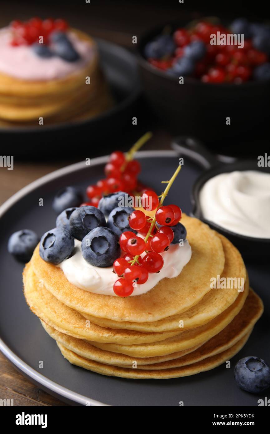 Tasty pancakes with natural yogurt, blueberries and red currants on wooden table Stock Photo
