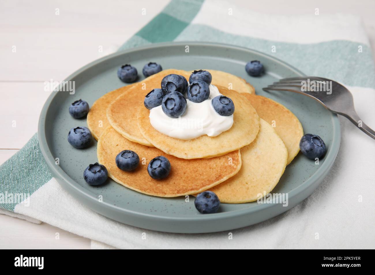 Tasty pancakes with natural yogurt and blueberries on white wooden table Stock Photo