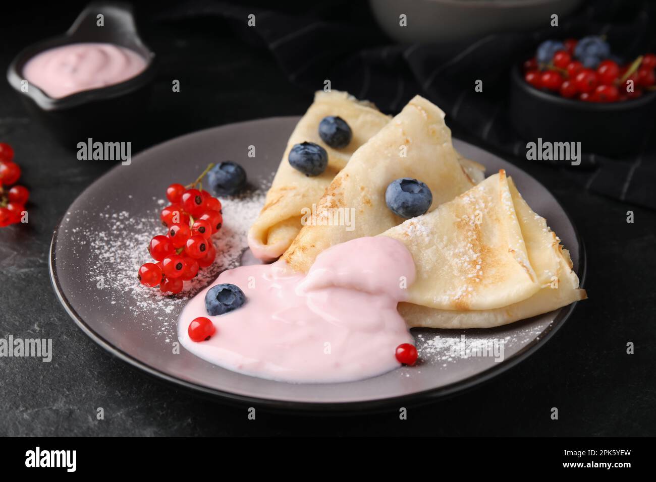 Delicious crepes with natural yogurt, blueberries and red currants on dark grey table Stock Photo