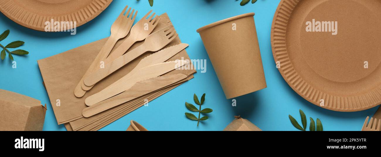 Paper and wooden tableware with green twigs on turquoise background ...