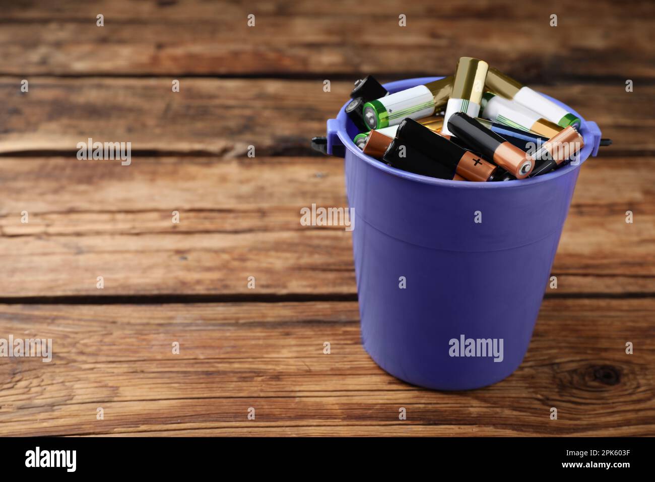 Used batteries in bucket on wooden table, space for text Stock Photo