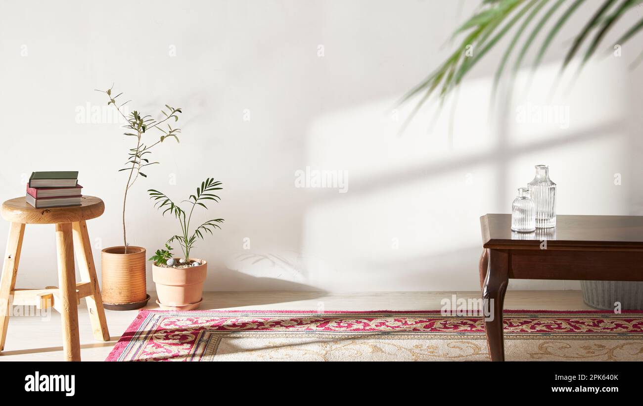 A room with a calm atmosphere, with clay pots placed in front of the wall and curtains letting in natural light. Glass bottles, coffee, and various ob Stock Photo